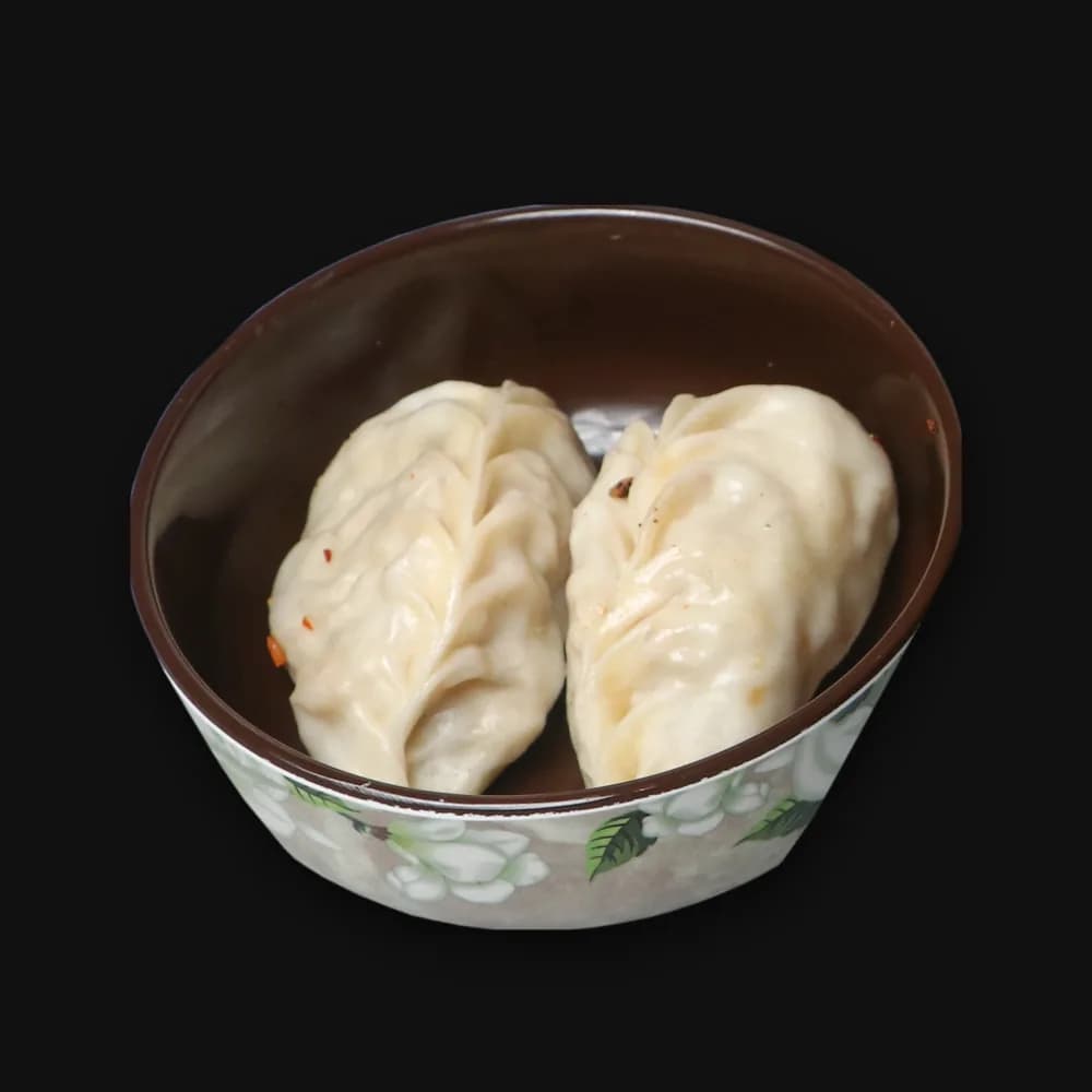 Two steamed momos in a small bowl