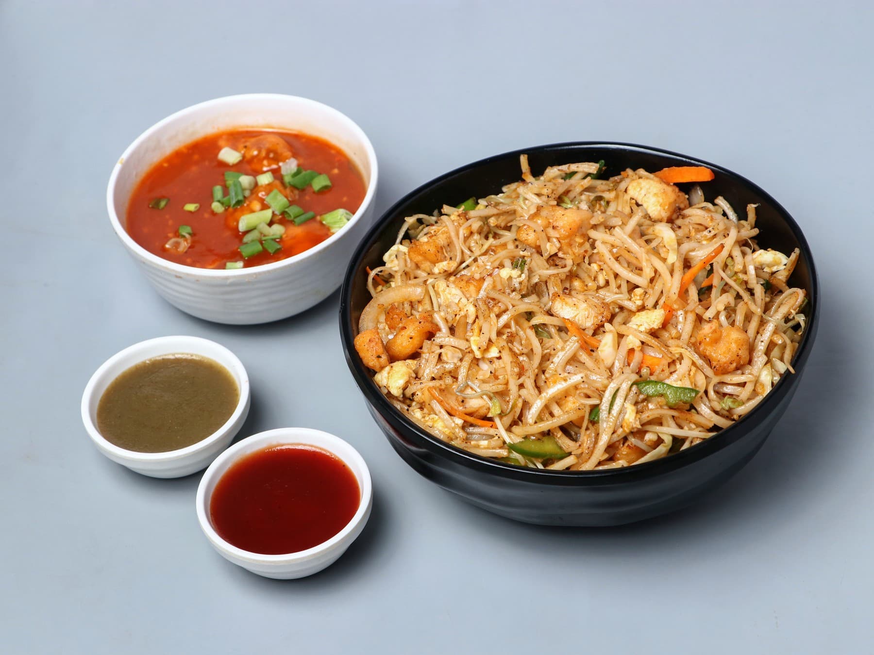 Chicken noodles in a black bowl with chilli garlic chicken gravy