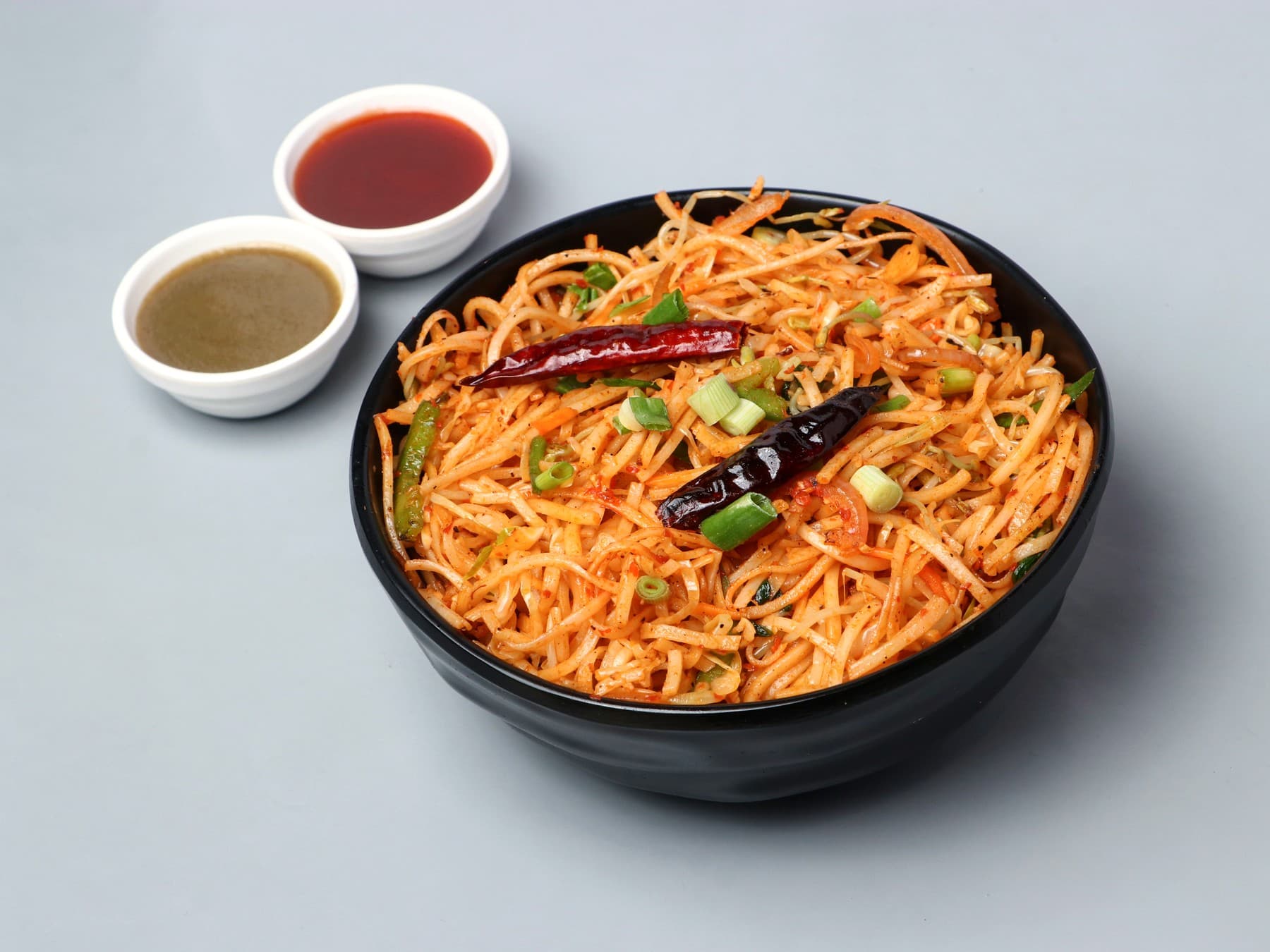 Red Schezwan noodles with dried chillies in a black bowl