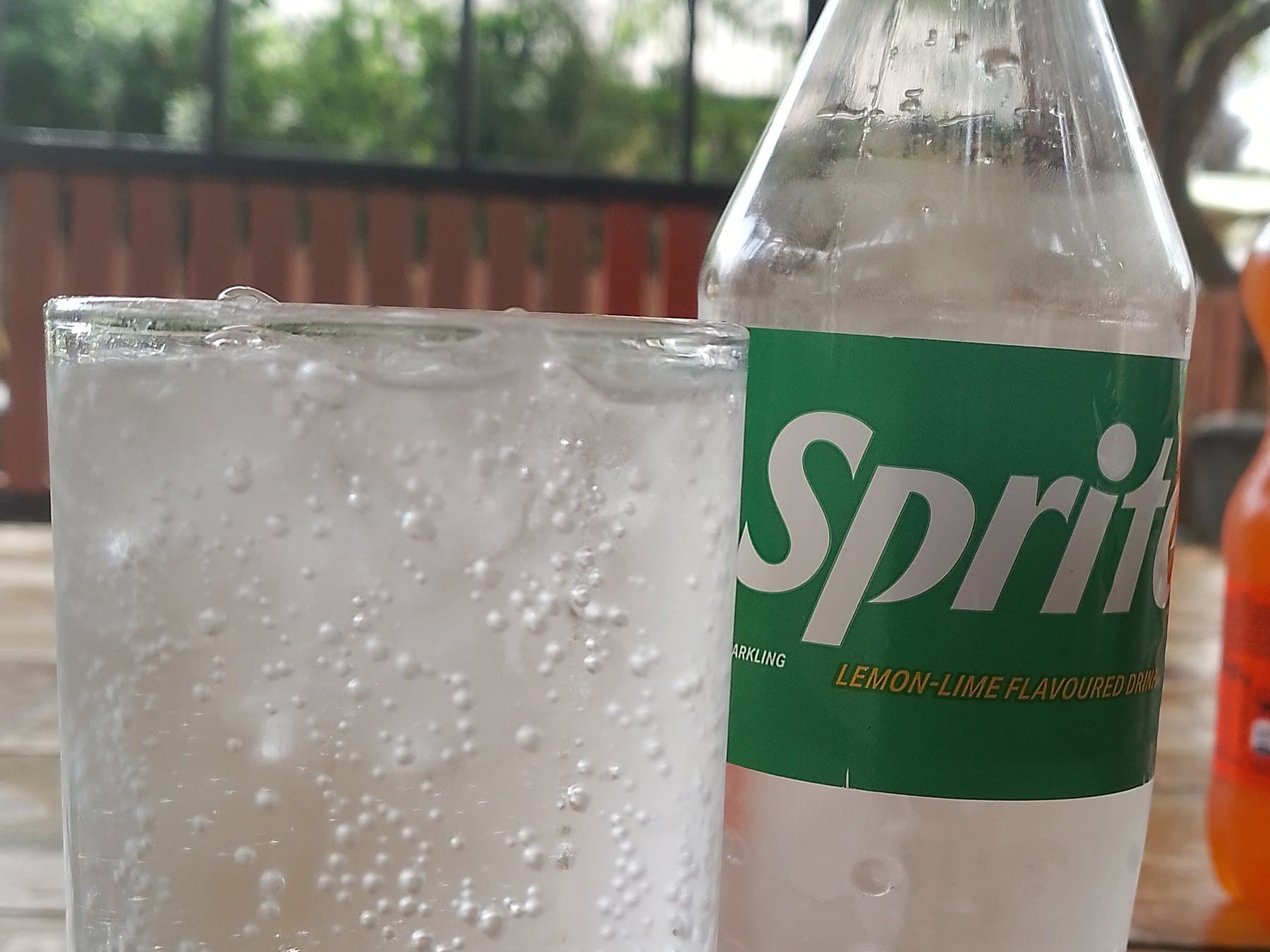 A bottle of Sprite beside a glass of fizzing Sprite
