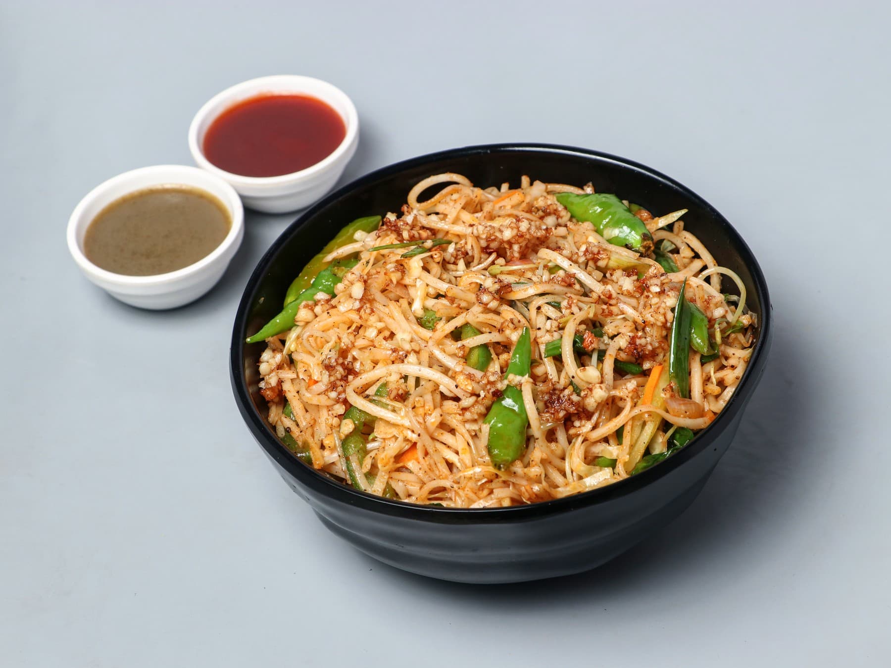 Chilli garlic noodles with green chillies in a black bowl