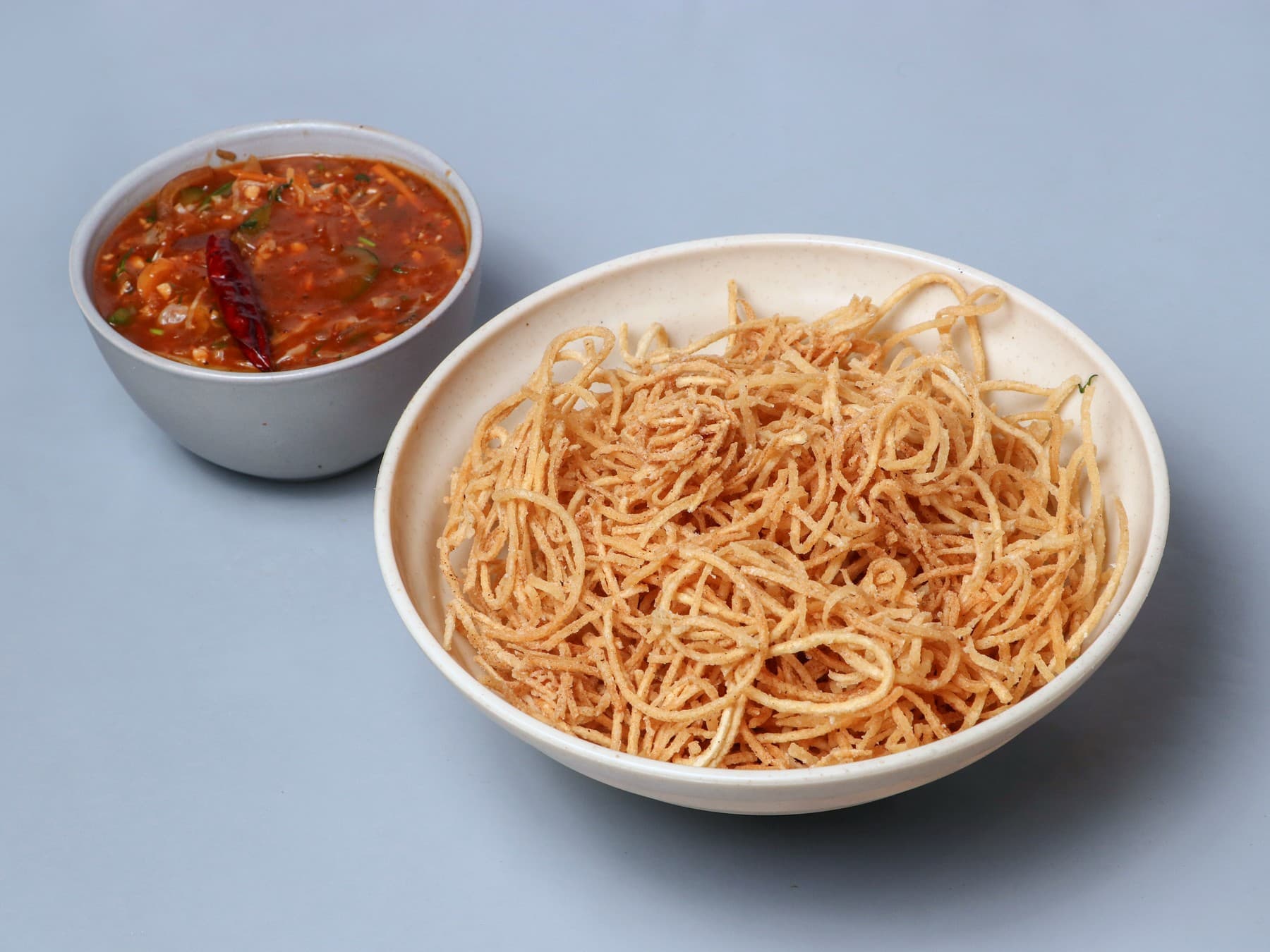 Crispy fried noodles with a bowl of Schezwan gravy