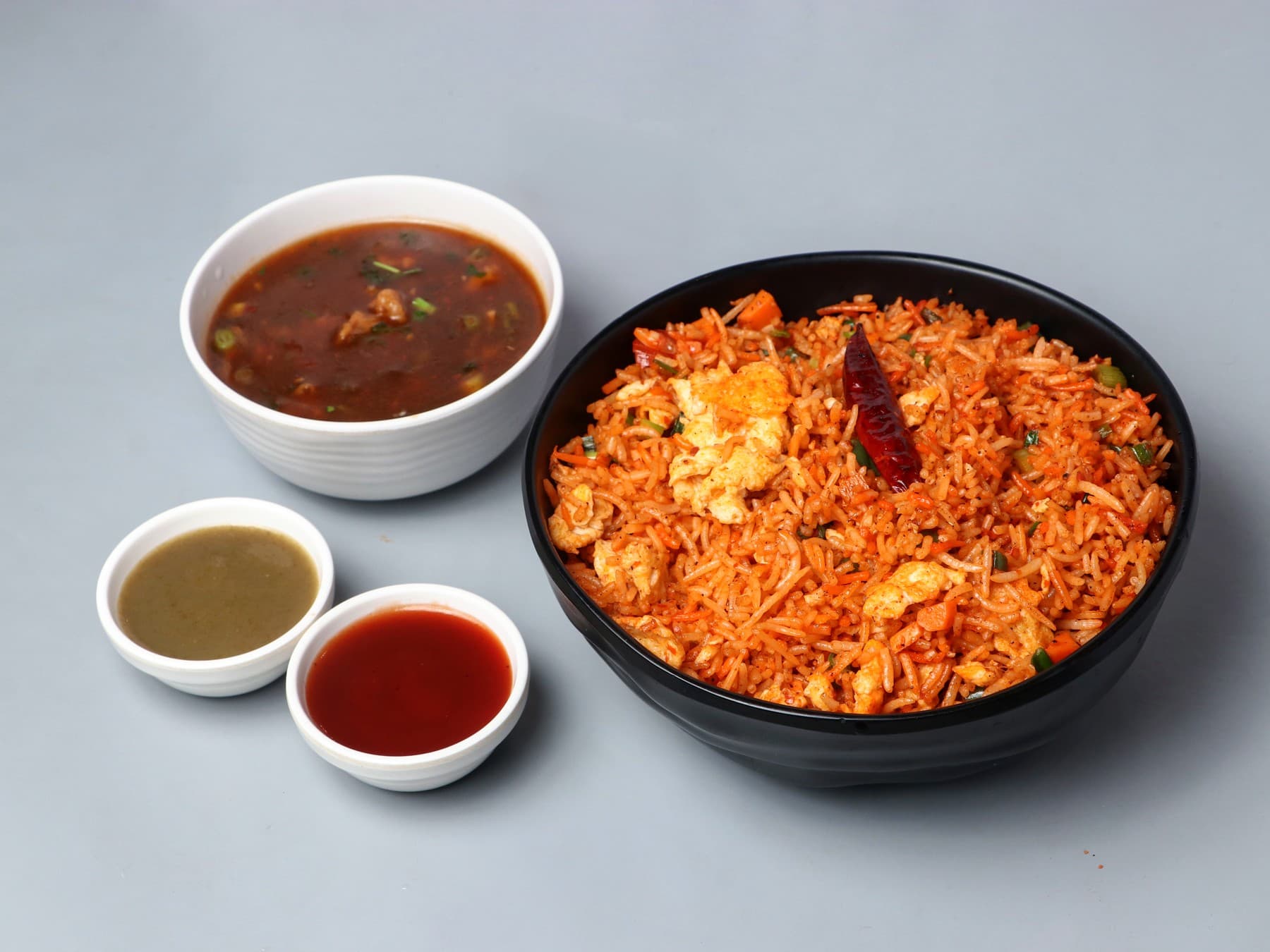 Schezwan egg fried rice with a bowl of chicken gravy