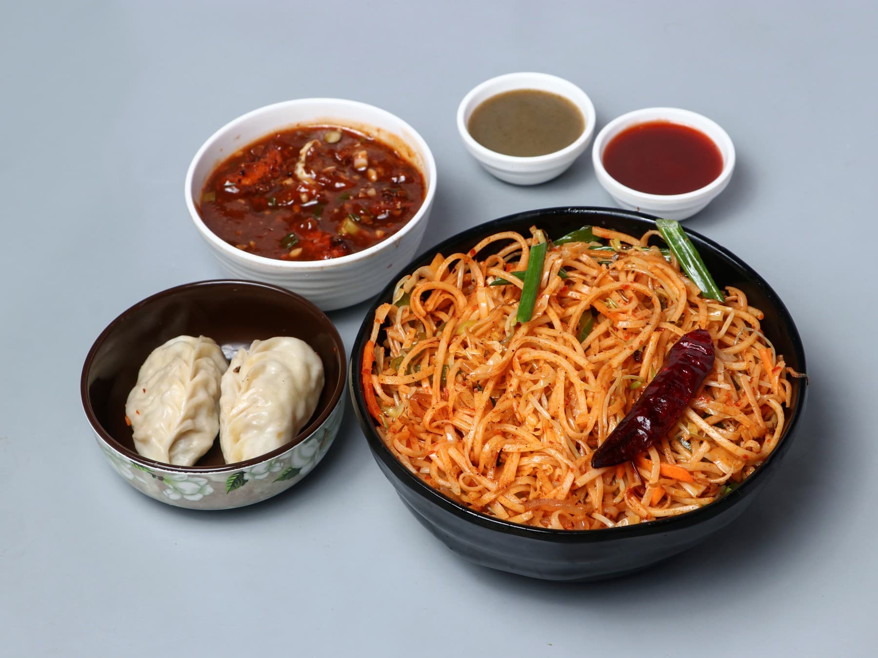 Schezwan noodles with momos, gravy and dips